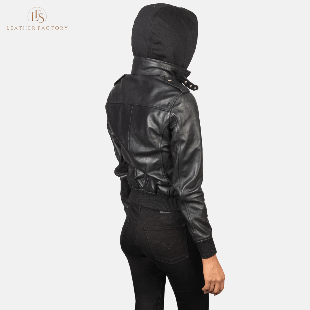 Woman wearing the Roslyn black sheepskin hooded leather bomber jacket featuring a high neck with belt, shoulder epaulettes, and a removable fabric hood.